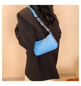 Detail of blue crocodile pattern shoulder bag with decorative plastic chain strap