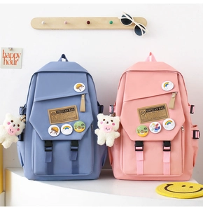 Detailed view of blue and pink nylon school backpacks with decorative plush bear charms