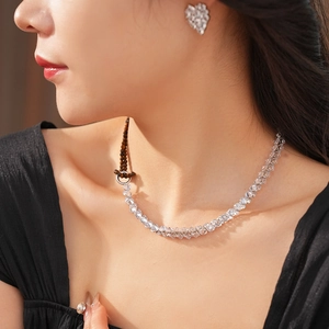 Macro shot of silver tennis necklace and heart stud earrings with zircon on model