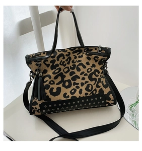 Detail view of leopard print canvas tote with black leather fringe and metal studs