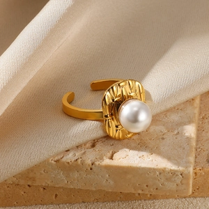 Detail of gold open ring with a large white pearl on an elegant silk and stone backdrop
