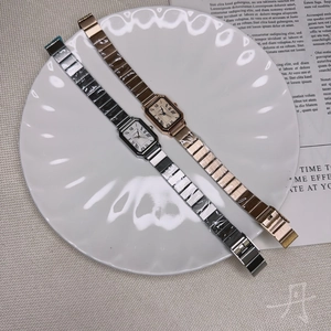 Close-up of rectangular quartz watches with metal link straps on a decorative plate