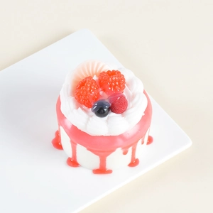 Detailed top view of faux cake with cream, red raspberries, and pink dripping syrup