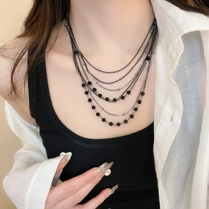 Detail shot of multi-layered black beaded necklaces styled on a model's neck