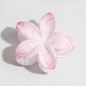 Detailed macro view of pink and white marble plumeria hair claw clip with acetate texture