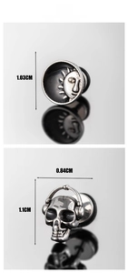 Gros plan de boucles d'oreilles punk avec motif soleil et crâne avec casque audio