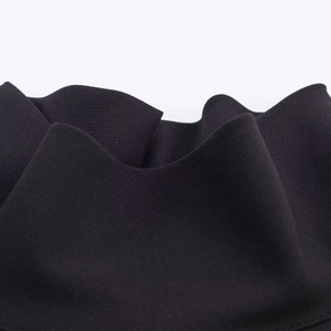 Dettaglio macro di un abito nero senza maniche con orlo a balze e trama in maglia fine