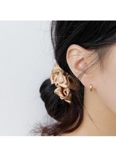 Close-up of small golden textured hoop earring with diamond-cut finish on woman ear