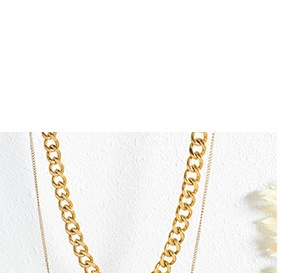 Close-up of golden chunky chain necklace featuring mixed link textures and metallic shine