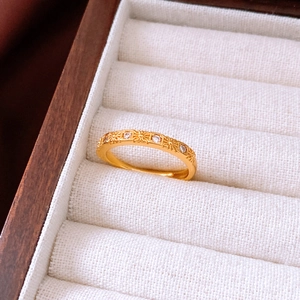 Détail d'une bague croix plaquée or avec zircons sertis sur un présentoir à bijoux en lin