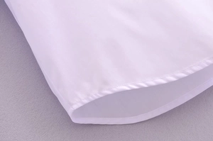 Detail shot of the hem showing the fine stitching and white cotton blend fabric texture