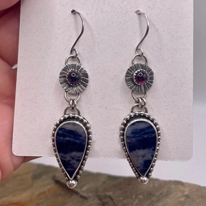 Detailed macro of vintage silver teardrop earrings with purple and blue gemstones