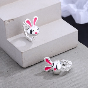 Silver rabbit earrings with pink enamel heart details on a grey stone background