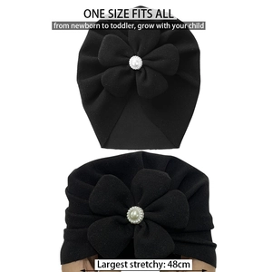 Detail of black stretchy baby turban hat with a pearl flower and size info up to 48cm