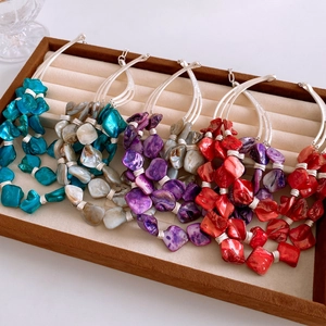 Detail of colorful geometric shell pendants with silver wire wrapped frames in a velvet box