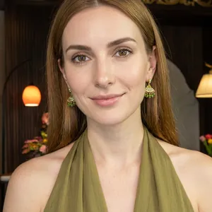 Detailed close-up of a model wearing bohemian green beaded teardrop raffia earrings