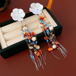 Detail of silver flower earrings with colorful tassels and beads on velvet padding