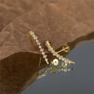 Close-up of S925 sterling silver C-shaped gold earrings with pearls and crystals
