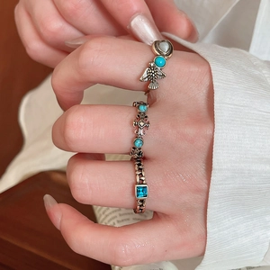 Detail of vintage bronze owl and cross ring set with turquoise and blue gemstone