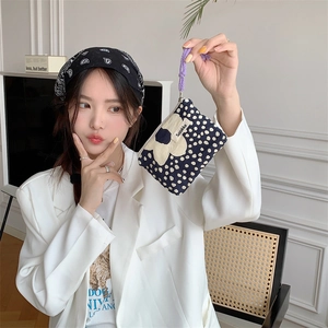 Close-up of canvas drawstring coin purse with blue polka dots and a large beige flower