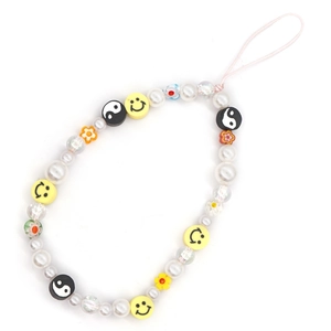 Détail du cordon de téléphone perlé avec perles blanches, smileys et breloques yin-yang