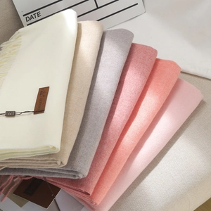 Stack of thick solid-colored scarves in various neutral tones with cashmere-like texture