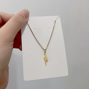 Detailed close-up of a minimalist gold lightning bolt pendant on a thin link chain necklace