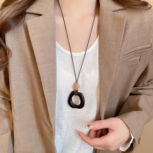 Close-up of a resin wood pendant necklace worn with a khaki blazer for a vintage look