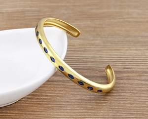 Detail shot of 18k gold-plated C-shaped cuff bracelet with oval blue zircon stones