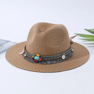 Dettaglio di cappello in paglia con perline colorate, pietre turchesi e nappe con frange
