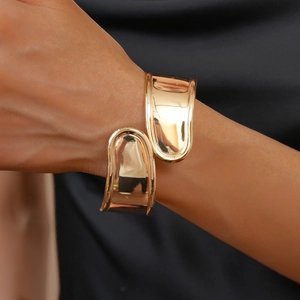 Close-up of a high-polished gold irregular open bangle on a model's wrist with mirror finish