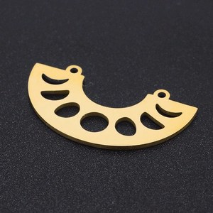 Detail of gold crescent moon connector with moon phase cutouts on black surface