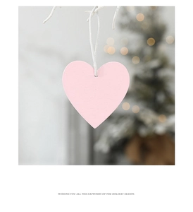 Pink heart-shaped wooden ornament with natural grain texture hanging on a branch