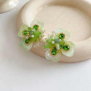 Détail de la boucle d'oreille fleur avec pétales verts, émeraude et petites perles