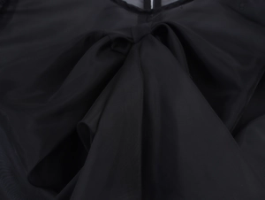 Gros plan sur le grand nœud noir en organza d'un chemisier à manches bouffantes