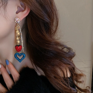 Close-up of dangling star strawberry heart tassels on long golden earrings
