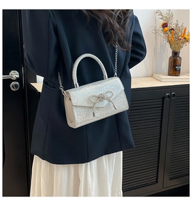 Chic silver sequin crossbody bag with rhinestone bow shown on a shoulder