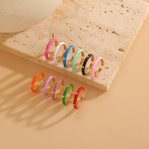 Detail of colorful enamel gold rings with zircon stones on textured stone surface