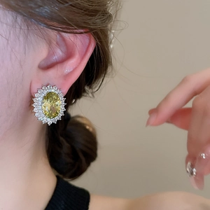 Macro view of vintage oval yellow zircon earrings with silver needles and crystal details