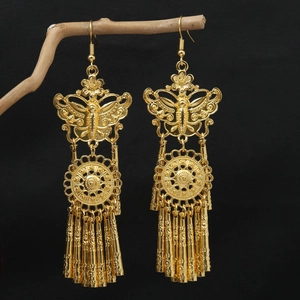 Detailed close-up of golden ethnic tassel earrings with butterfly motifs and leaf pendants