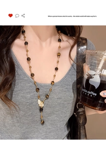 Detailed view of long tiger eye beaded necklace with gold leaf zircon pendant on model