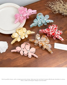 Close-up of assorted acetate flower hair claws with rhinestone centers in six colors