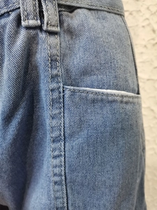 Dettaglio ravvicinato di pantaloncini in denim blu con cuciture rinforzate e tasche curate