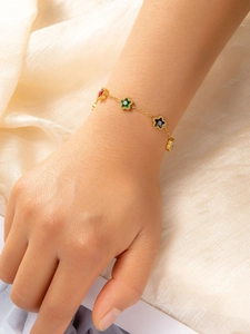Close-up of gold star bracelet with red green and black zircon charms on silk