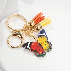 Colorful butterfly tassel keychain with orange and yellow fringes on white background