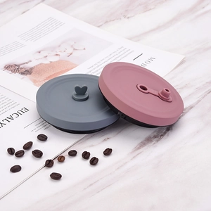 Silicone lid set with heart handle and pull ring on marble surface with coffee beans