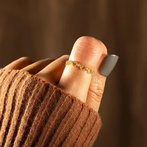 Détail d'une bague coeur ajourée dorée avec zircons étincelants portée au pouce