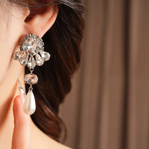 Close-up of model wearing vintage flower pearl earrings with sparkling diamond studs