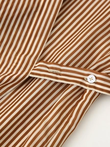 Close-up of brown and white vertical stripes on a casual shirt dress with button detail