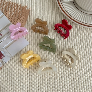 Set of colorful heart-shaped hair claws in assorted pastel colors on a woven fabric